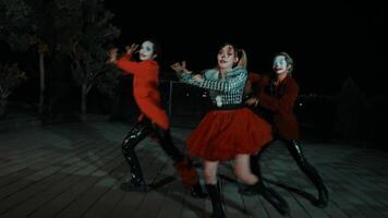 tre människor i halloween kostymer dans på natt med läskigt masker och färgrik kläder. video