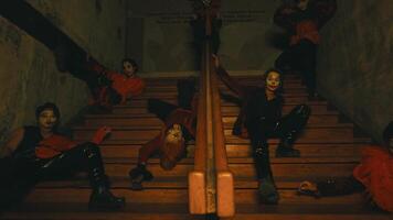 un' gruppo di pagliacci con raccapricciante trucco seduta e in posa su un vecchio scala nel un' frequentato edificio video