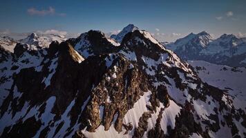 rouge majestueux rochers saupoudré avec neige haute dans le montagnes. en volant près haute pics et Montagne hauts à le coucher du soleil. aérien vue horizontal stabilisé image video