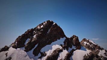 aéreo Visão do Nevado montanha alcance paisagem, debaixo azul céu, inverno cenas a partir de zangão 4k video