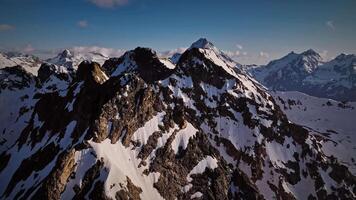 aereo Visualizza volante in giro un' snow-capped picco alto nel il montagne. naturale sfondo girato con un' drone. video