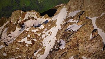 Antenne Aussicht fliegend Über ein Berg Angebot im Vorderseite von ein hoch felsig Berg Gipfel beim Sonnenuntergang. hoch Kontrast, stabilisiert Aufnahmen Schuss von das Luft. Berge im früh Frühling video