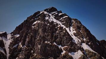 antenne visie van een rotsachtig berg top hoog in de bergen Aan een zonnig dag. Nee een in de kader. recensie in de bergen video achtergrond natuurlijk