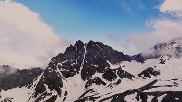 aerial view flying over a mountain range in front of a high rocky mountain peak at sunset. High contrast, stabilized footage shot from the air. Mountains in early spring video