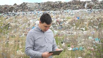 Garbage dump inspector with tablet records pollution level. Ecology pollution concept video