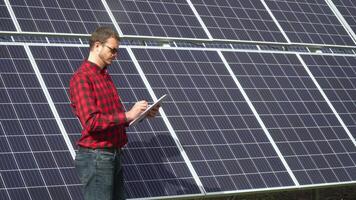 Successful young engineer planning futuristic solar panels power plant. Engineer checks solar panels productivity video