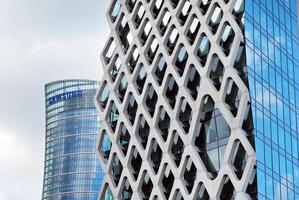 Structural glass wall reflecting blue sky. Abstract modern architecture fragment. photo