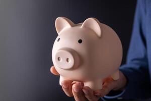 saving money wealth and financial investment concept.businessman holding pink piggy bank in his hand photo