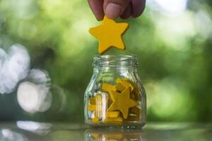 Put yellow star to a glass jar with many stars. Giving the highest mark for service. Giving social credit photo