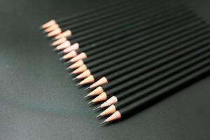 Stack of black pencil on the matte black background photo