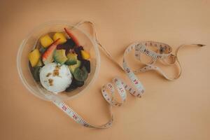 Fresco yogur y tropical Fruta ensalada para desayuno en un cuenco con blanco medición cinta foto