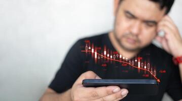 Man using mobile phone checking stock market graph report via mobile apps trading decreasing chart data fall. photo