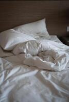 White pillow with blanket on bed unmade. Concept of relaxing after morning. photo