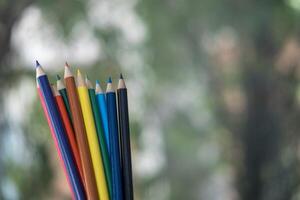 Color pencils over green nature blur background photo