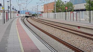 Nules-La Vilavella, Spain 10.09.2023 Train Station Platform, Quiet railway platform with oncoming train at a station in Valencia, Spain, under a clear sky. video