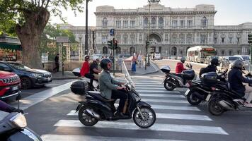 Rome, Italië 29.10.2023 bezig stedelijk straat met scooters en klassiek architectuur, automobilisten aan het wachten Bij een verkeer licht Aan scooters in een bruisend stad, met een historisch neoklassiek gebouw in de video