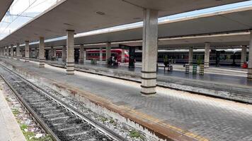 rom, Italien 29.10.2023 ödslig tåg plattform med på tomgång tåg, gles passagerare på en ledig tåg plattform med stationär tåg, under en samtida tak strukturera. video