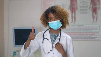 Portrait of professional african american female doctor in medical mask. Hospital with ultrasound devices on background. Stop virus video