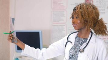 Female african-american doctor examines x-ray of lungs in clinic. Concept of medicine, health care and people video