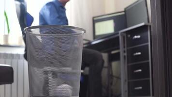 Office employee tossing away crumpled paper into trash can. Loafer at office, businessman throws papers in trash can video