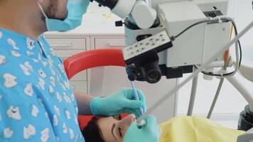 estomatólogo y paciente a clínico oficina. un hombre dentista en un médico guantes trabajos con un paciente niña en un dental oficina. cuidado de la salud y medicina concepto. odontología video