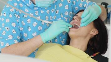 un hombre dentista en un médico guantes trabajos con un paciente niña en un dental oficina. cuidado de los dientes concepto. odontología video