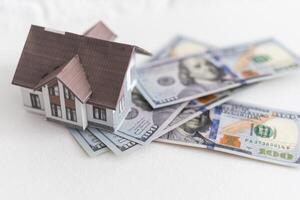 House standing on a pile of dollar bills. Investment, real estate and property concept photo