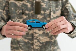 a military man is holding a toy car. photo