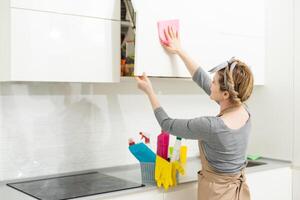 mujer limpieza y pulido el cocina encimera con un rociar detergente, limpieza interna y higiene concepto. foto