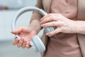 Female hand hold a stereo headphones isolated on white background. photo