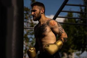 Man in boxing gloves is practicing on an outdoor photo