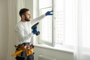 service man installing window with screwdriver photo