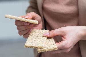 Hand with salty cracker, crispy appetizer, rectangle shape cookie. Isolated on white background. photo