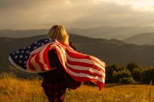 Young woman holding American flag on sky background photo