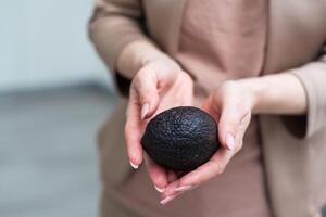 Woman hand holding avocado on white background, closeup photo