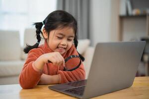 Curious Girl Exploring with Magnifying Glass and Laptop. Smiling young girl with pigtails using a magnifying glass to look at a laptop screen, showing curiosity and joy. Education for kids concept. photo
