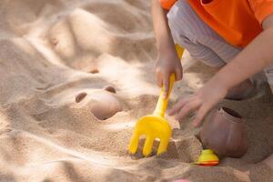 Close-up hand. Asian girl children playing sand on the playground in the cafe for kids. Little girl playing in the sand on the playground. Healthy active baby outdoors plays games concept. photo