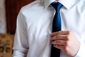 Groom's morning preparation, groom getting dressed and preparing for the wedding. Stylish groomsmen. Businessman. Luxury man in suit in room. Closeup photo