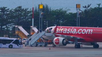 PHUKET, THAILAND - FEBRUARY 27, 2023. Boarding on the plane AirAsia. People go up the stairs to the aircraft. Passenger plane. Travel concept. video