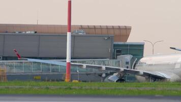 KAZAN, RUSSIA - AUGUST 05, 2022. Passengers are on telescopic gangway from the airplane Nordwind. People walk along the passageway of the airport to the exit to the plane with bags and suitcases video