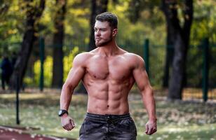 Muscular shirtless man fitness model posing outdoor in a sunny sport yard. Nice muscular body. Half weist photo. Closeup. photo