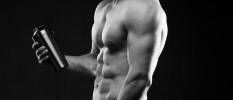 photo of half naked sportsman holding bottle of water. Cropped photo studio indoor. Close-up. Black and white