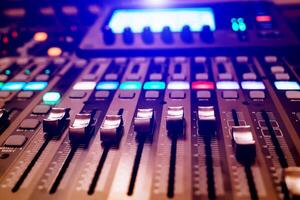 a professional concert mixing console with faders is used by a DJ for recording music. Close-up photo
