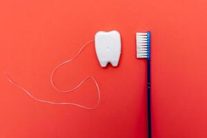 White glitter tooth with toothbrush on red background. Treatment with tooth. photo