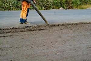 worker blows out the pieces of old asphalt and stones from the pits by leaf blower on the road. Close up photo