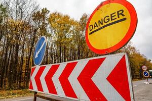 Danger road sign on road in red circle on yellow color. Warning ahead. Pointer on blue color in circle. photo