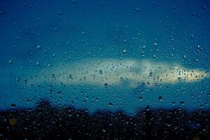 de cerca de gotas en ventana. antecedentes de Moviente lluvia gotas en un ventana vaso en un lluvioso día. foto