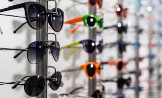 Sunglasses in a store. Ssunglasses in the shop display shelves. photo