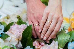 A pair of gold wedding rings on a bride's and groom's hands. Closeup. photo