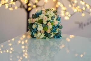 Beautiful and colourful bouquet of flowers over white table with blurred lights background photo